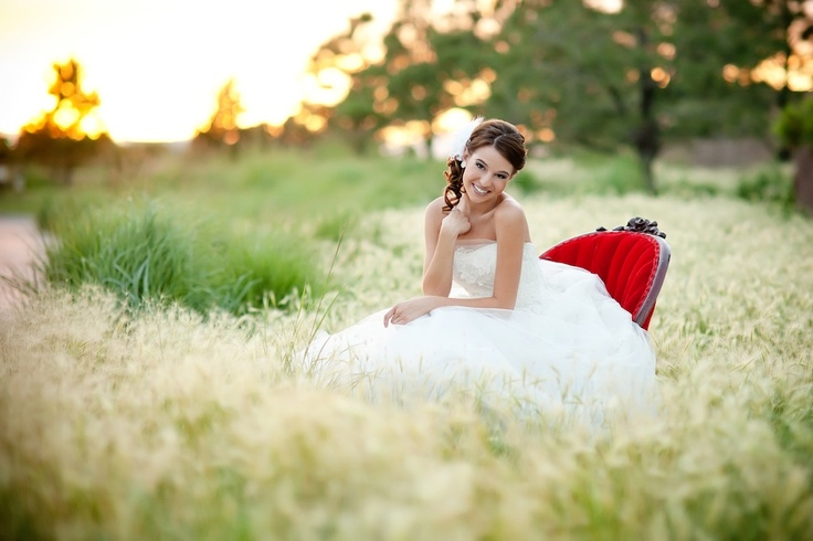 Photo by Keri Doolittle Photography - Look at the field as rippling waves of grass and greenery for a moment. There in the middle is our beautiful pearl of a bride, seated casually in her ruby red oyster shell style settee, the focal point of the photograph with color, focus, and pose.