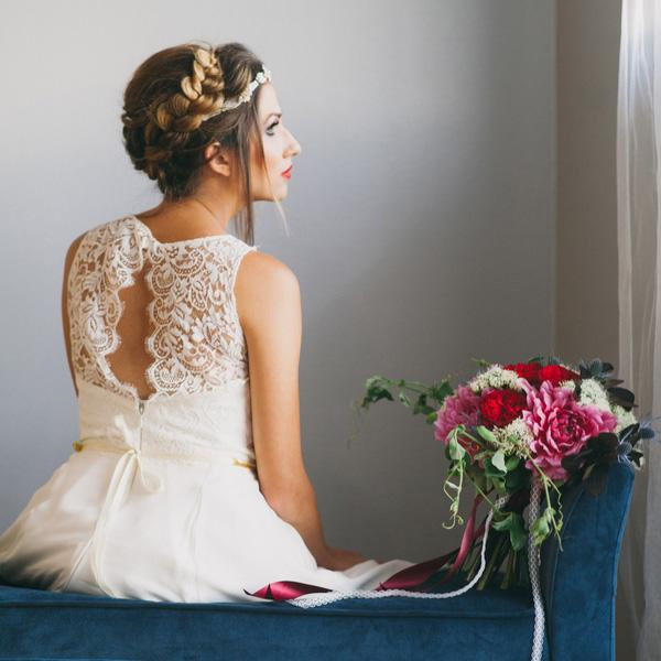 Photo by Alexandra Wallace Photography - The blue velvet bench and rich red and pink bouquet draw just enough attention away from the backward-facing bride so that you feel you’ve captured a private thought. This pose is a brilliant way to show off a wedding gown’s decorative back.